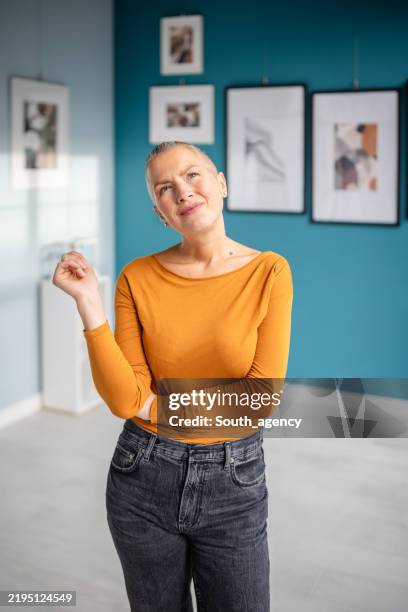 art enthusiast poses thoughtfully in bright gallery space filled with engaging artwork - espetáculo de arte imagens e fotografias de stock