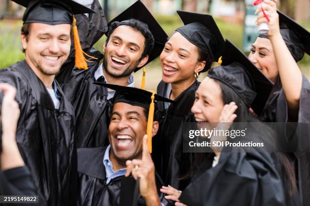 joyful diverse graduates celebrating success together - diverse graduation stock pictures, royalty-free photos & images