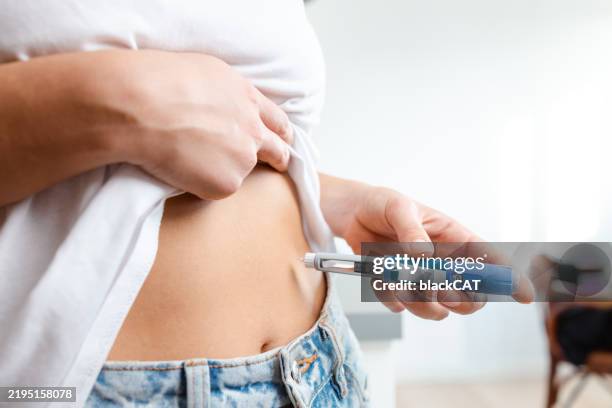 person administering insulin injection using a pen - seringa imagens e fotografias de stock