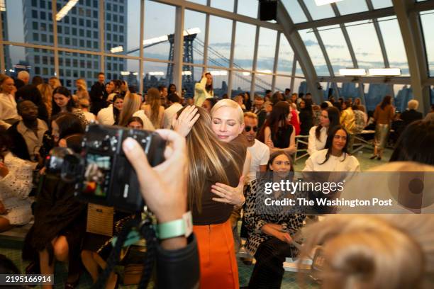Actress Michelle Williams greets actress Joey King with a warm embrace before the start of the Tory Burch SS25 Runway Show at Skylight at The...