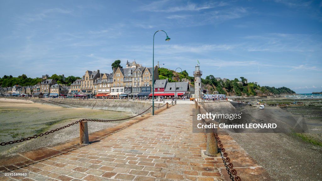 Wide angle view of the quays of Cancale with traditional Breton stone houses, restaurants, cafe terraces and its beach, as seen from the main cobblestone jetty, Ille-et-Vilaine - Bretagne (Brittany) - Western France.
