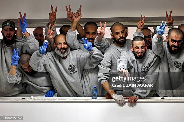 Palestinian prisoners released by Israel wave and cheer to people below gathering to receive them at a sports centre building of the Ramallah...