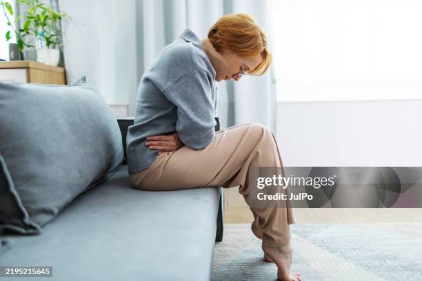 donna adulta media che soffre di mal di stomaco - mal di pancia foto e immagini stock