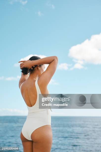 woman in white swimsuit enjoying a scenic coastal view under clear blue skies - badkläder bildbanksfoton och bilder