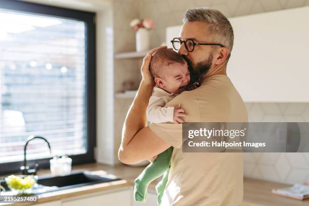 crying baby in fathers arms. dad trying to calm, soothe newborn, kissing him on head. concept of paternity leave. - larme photos et images de collection