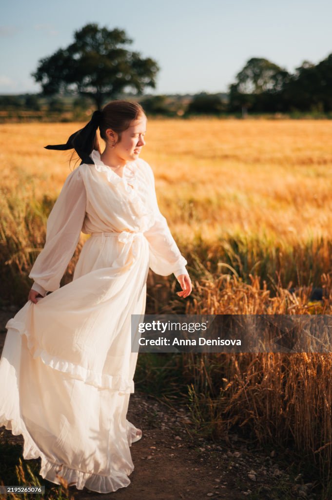 Young girl in golden wheat field during sunset
