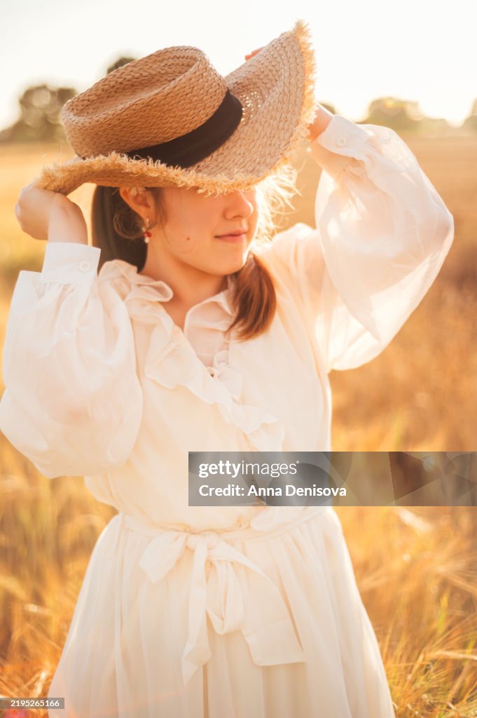 Young girl in golden wheat field during sunset