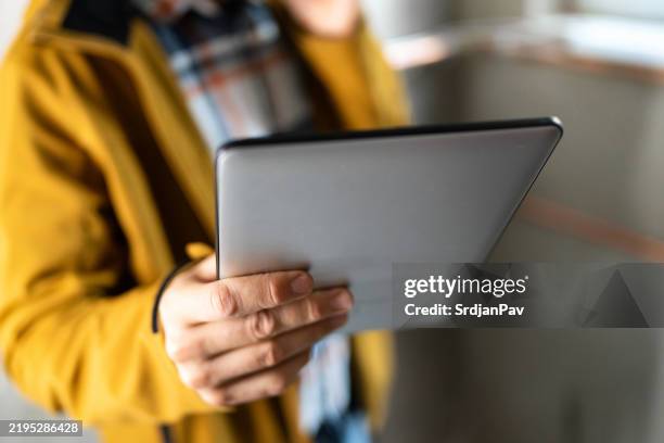 person, die ein tablet in innenräumen hält, trägt ein lässiges outfit in nahaufnahme - heizungsmonteur stock-fotos und bilder