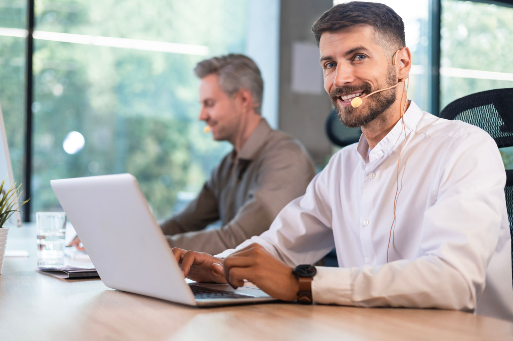 Young handsome male customer support phone operator with headset working in call center. Young handsome male customer support phone operator with headset working in call center.