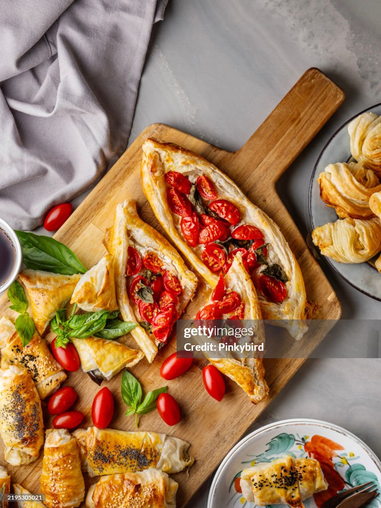 Turkish pita. Turkish Pide. Margherita Flat Bread Pizza. Turkish pide with pastry on the board. Homemade feta cheese puff pastry. Puff pastry pie with tomatoes and basil. Savory Tarts. Tomato Quiche. Tomato Tart. Delicious fresh cheese pita.