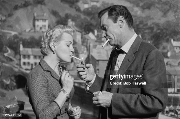 Actor Barry Sullivan lights a cigarette for actress Lana Turner while acting outdoors in the film "Another Time, Another Place", Elstree Studios,...