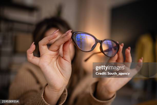 woman showcasing stylish cat-eye glasses in cozy indoor setting during daytime - bril stockfoto's en -beelden