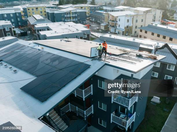 technicians work on solar panel installation in housing development high angle view - energy efficient building stock pictures, royalty-free photos & images