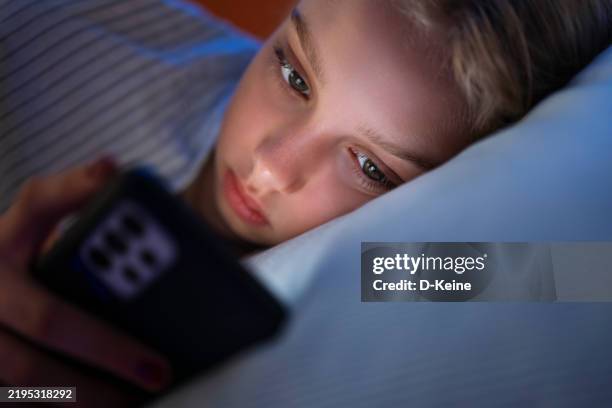 young girl using smartphone in bed at night - girls stock pictures, royalty-free photos & images