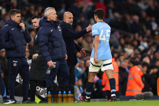 Abdukodir Khusanov of Manchester City with Manager Pep Guardiola after he is substituted for John Stones during the Premier League match between...
