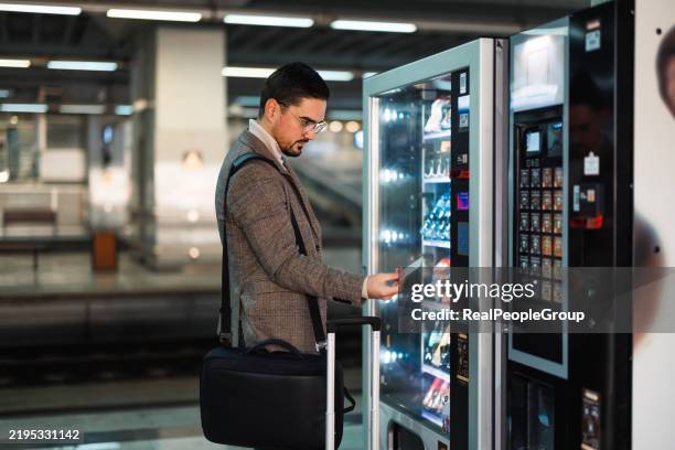 businessman buying snacks at vending machine in train station - verkoopautomaat stockfoto's en -beelden