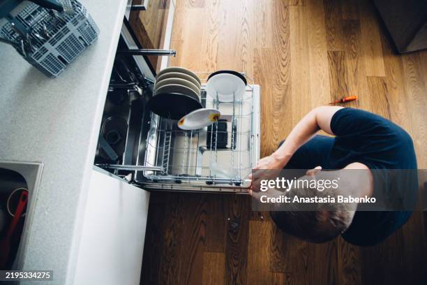 high angle view of man fixing dishwasher - repatriation stock pictures, royalty-free photos & images