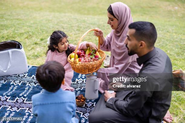 middle eastern family enjoying fresh fruits at park picnic - traditional clothing stock pictures, royalty-free photos & images