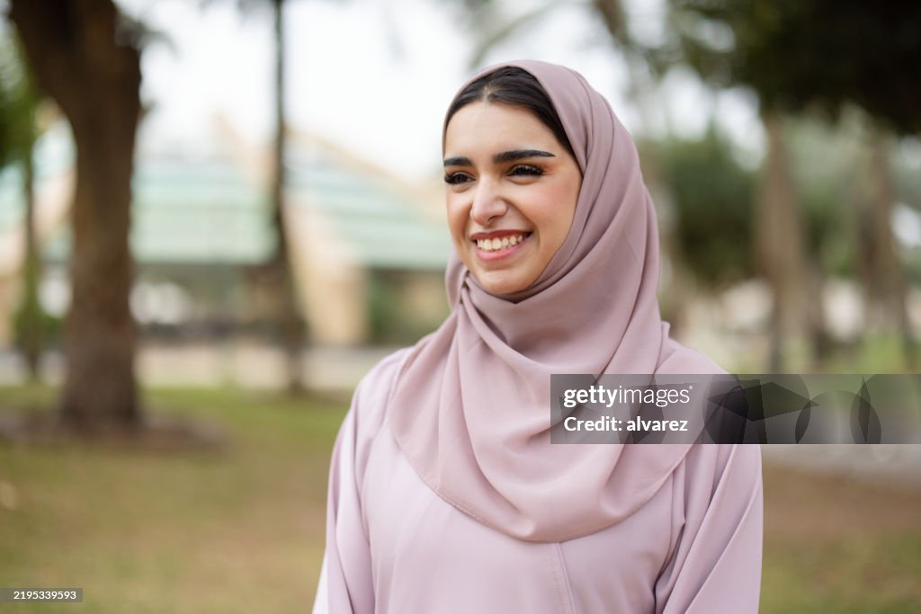 Saudi woman wearing a hijab and smiling at the park