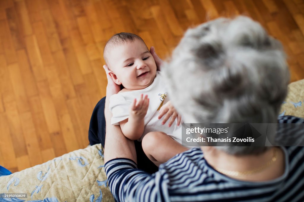 Joyful interaction between grandparent and baby at home