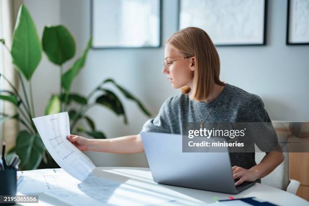 young architect working on laptop in modern workspace planning designs - plattegrond stockfoto's en -beelden