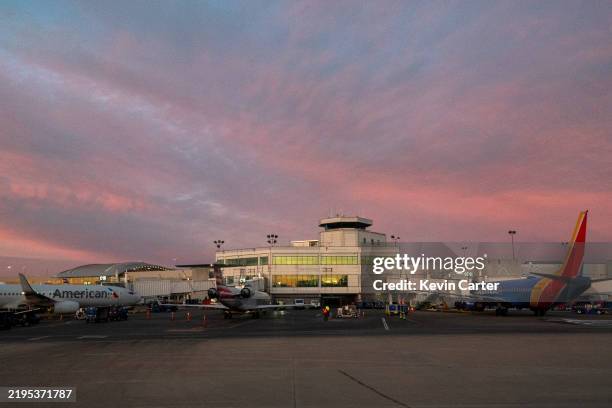 Airplanes are parked at jetways at Nashville International Airport at sunset on January 22, 2025 in Nashville, Tennessee.