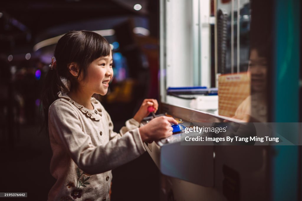 Happy young girl playing at an arcade game machine