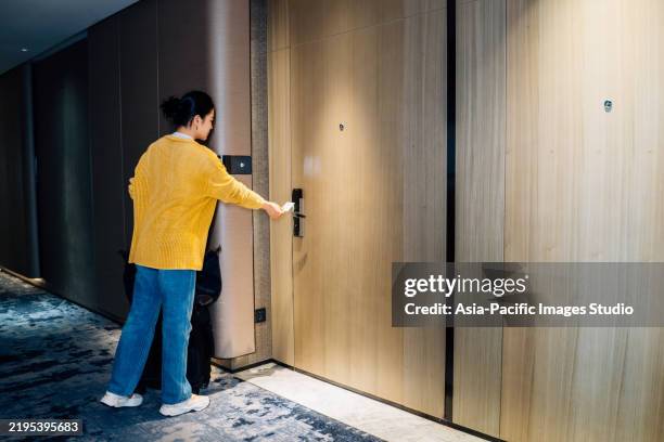 asiatische geschäftsfrau, die nach dem kontrollieren ihre hotelzimmertür mit einer schlüsselkarte öffnet. - hotelzimmer tür stock-fotos und bilder