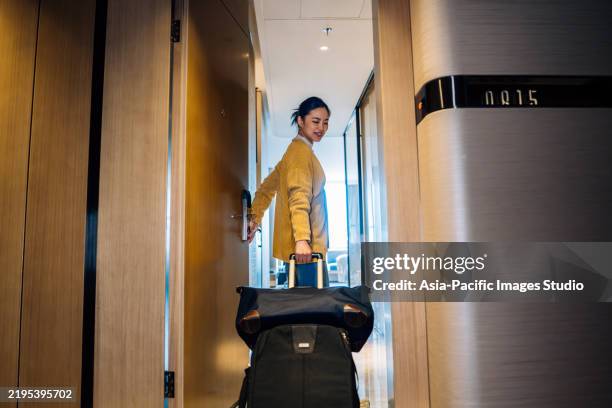 asiatische geschäftsfrau mit einem koffer und betritt das hotelzimmer. - hotelzimmer stock-fotos und bilder