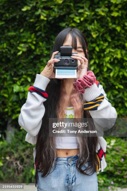 young woman using instant camera outdoors - analog stock pictures, royalty-free photos & images