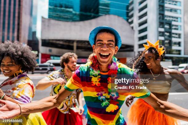 porträt eines mannes im mittleren erwachsenenalter, der mit freunden auf dem straßenkarneval tanzt - karneval feier stock-fotos und bilder