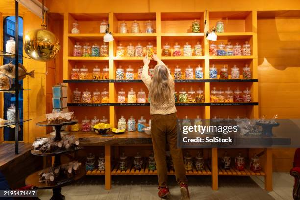 choosing a treat at an old fashioned sweet shop - confectioner stock pictures, royalty-free photos & images