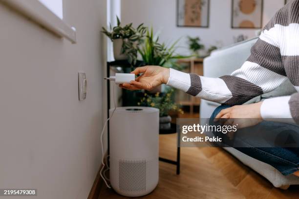 unrecognisable woman plugging in air purifier into electric socket - wired stock pictures, royalty-free photos & images