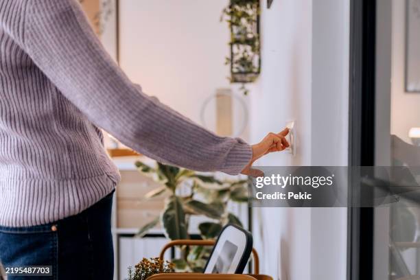 mujer irreconocible encendiendo el interruptor de la luz en casa - interruptor fotografías e imágenes de stock