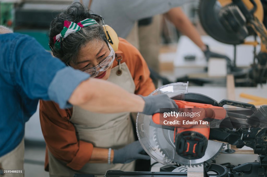 Asian senior woman learn how to use miter saw from carpenter on woodwork classes workshop