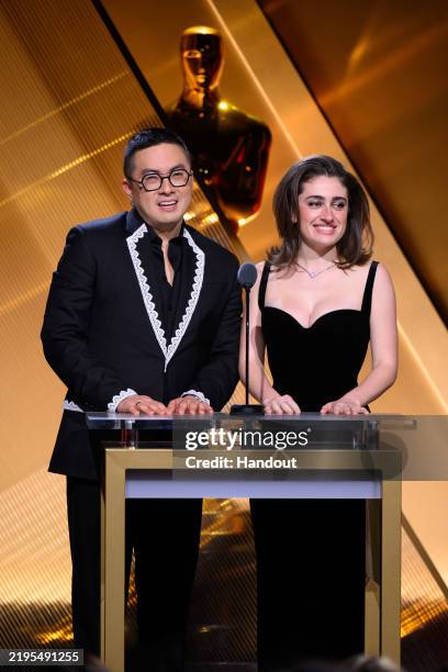 In this handout photo provided by The Academy, Bowen Yang and Rachel Sennott speak onstage during the 97th Oscars Nominations Announcement at Samuel...