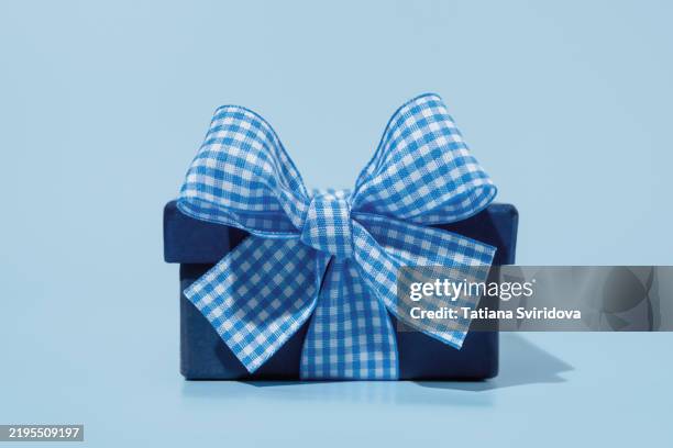 blue gift box with checked bow ribbon on blue background - birthday card table stock pictures, royalty-free photos & images