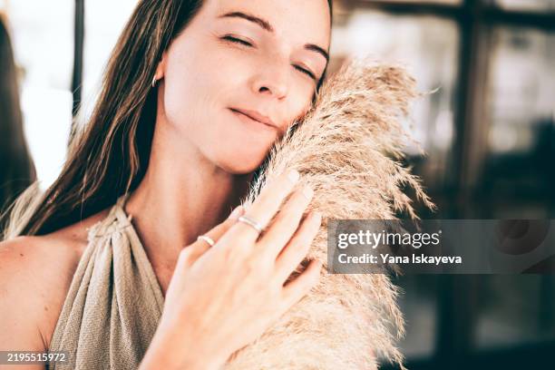 a serene blonde woman dreaming, holding the pampas grass - contraceptive patch stock pictures, royalty-free photos & images
