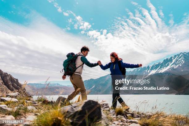 tourist man helping friend on a mountain, in cajon del maipo, chile - chile stock-fotos und bilder