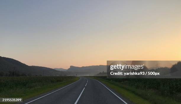 empty road amidst field against clear sky - point de fuite photos et images de collection