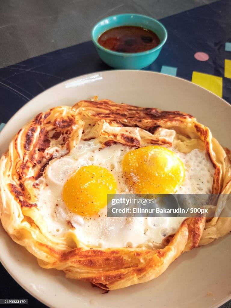 Roti sarang burung on the table It is pratha looks like bird nest with half cook eggs in the middle