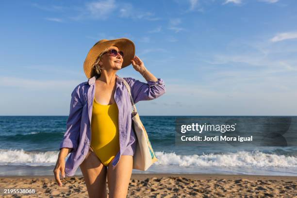 senior woman enjoying summer vacation on the beach - badkläder bildbanksfoton och bilder