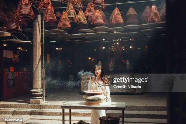 asian woman meditating at tin hau temple with burning incense sticks - frankincense stock pictures, royalty-free photos & images