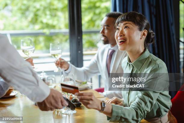 woman paying for meal at a restaurant while smiling at server - asian restaurant server stock pictures, royalty-free photos & images