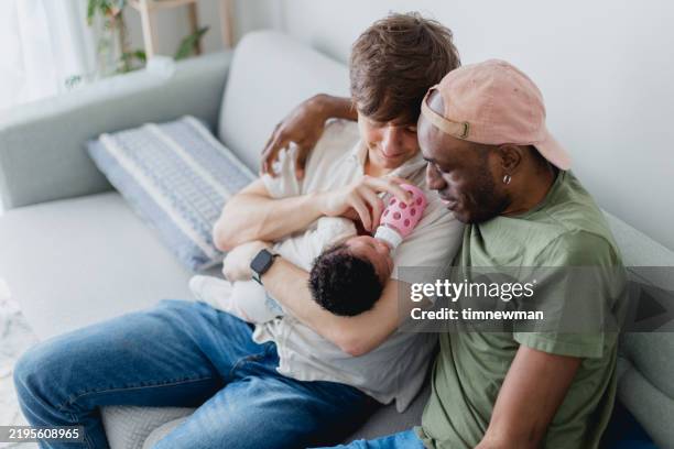 des papas gays donnent un biberon à leur bébé - remplacement photos et images de collection