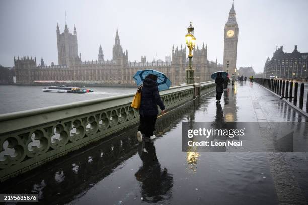 Commuters are battered by strong winds as they cross Westminster Bridge on January 24, 2025 in London, United Kingdom. The Met Office has issued rare...