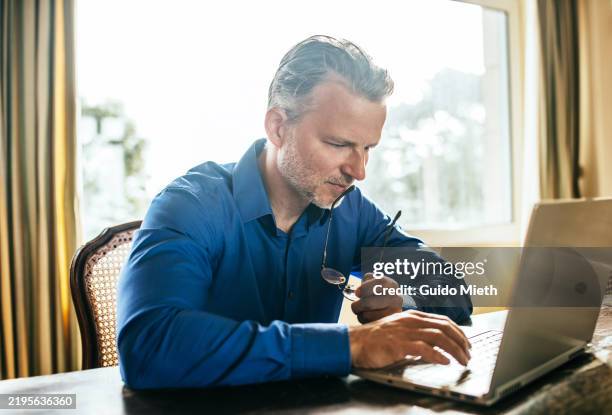 man shopping online with laptop and credit card. - hombres-de-mediana-edad fotografías e imágenes de stock