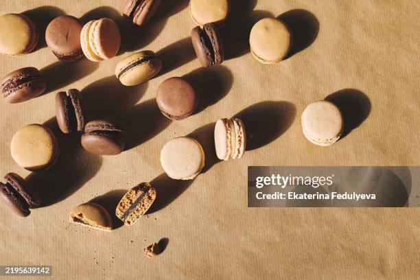 delicious macarons in mocha mousse tones on the colored beige background with shadows. trendy colors. color of the year 2025 mocha mousse. - mocha stock pictures, royalty-free photos & images