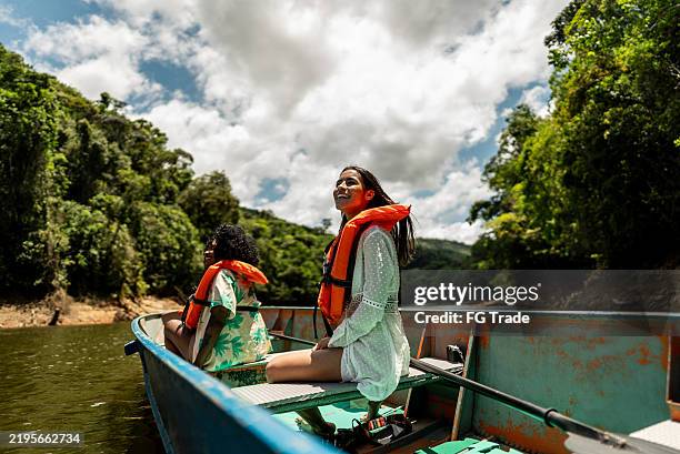 young tourist woman enjoying boat ride on river surrounded by forest - voyage expérientiel photos et images de collection