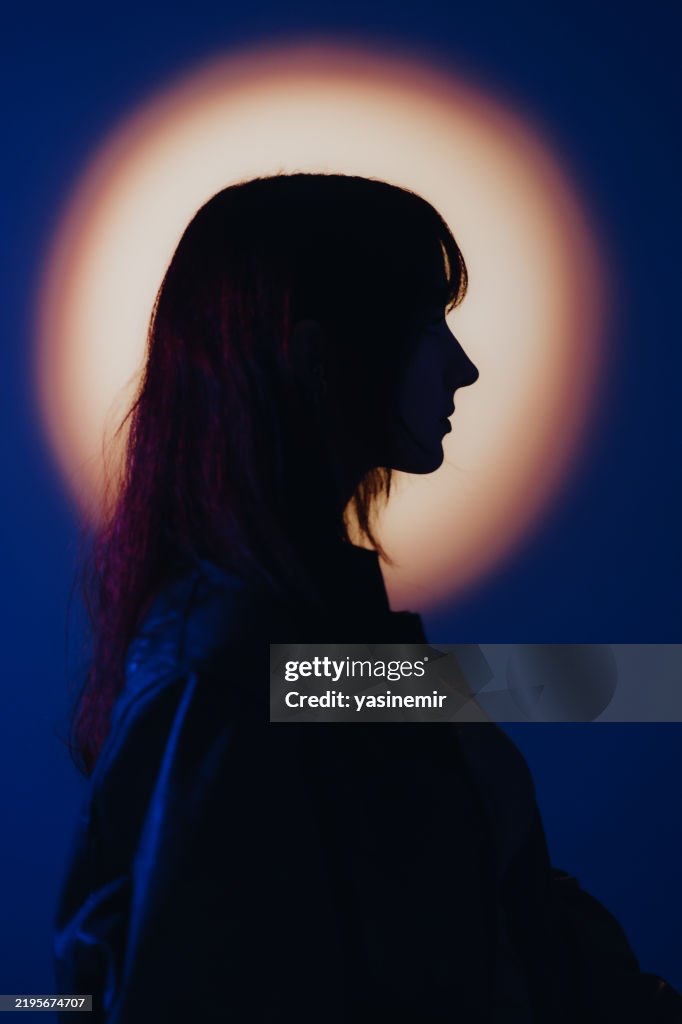 Young woman silhouette looking right on orange and purple background